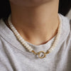 beaded necklace with a gold clasp worn by a person wearing a gray shirt.