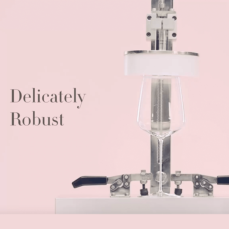 image depicting the strength of Stem Zero Wine Glasses, a robot is holding the glass thereby demonstrating the glasses strength against the very thin weight of the glass, it has a writing on the image: "delicately robost" 