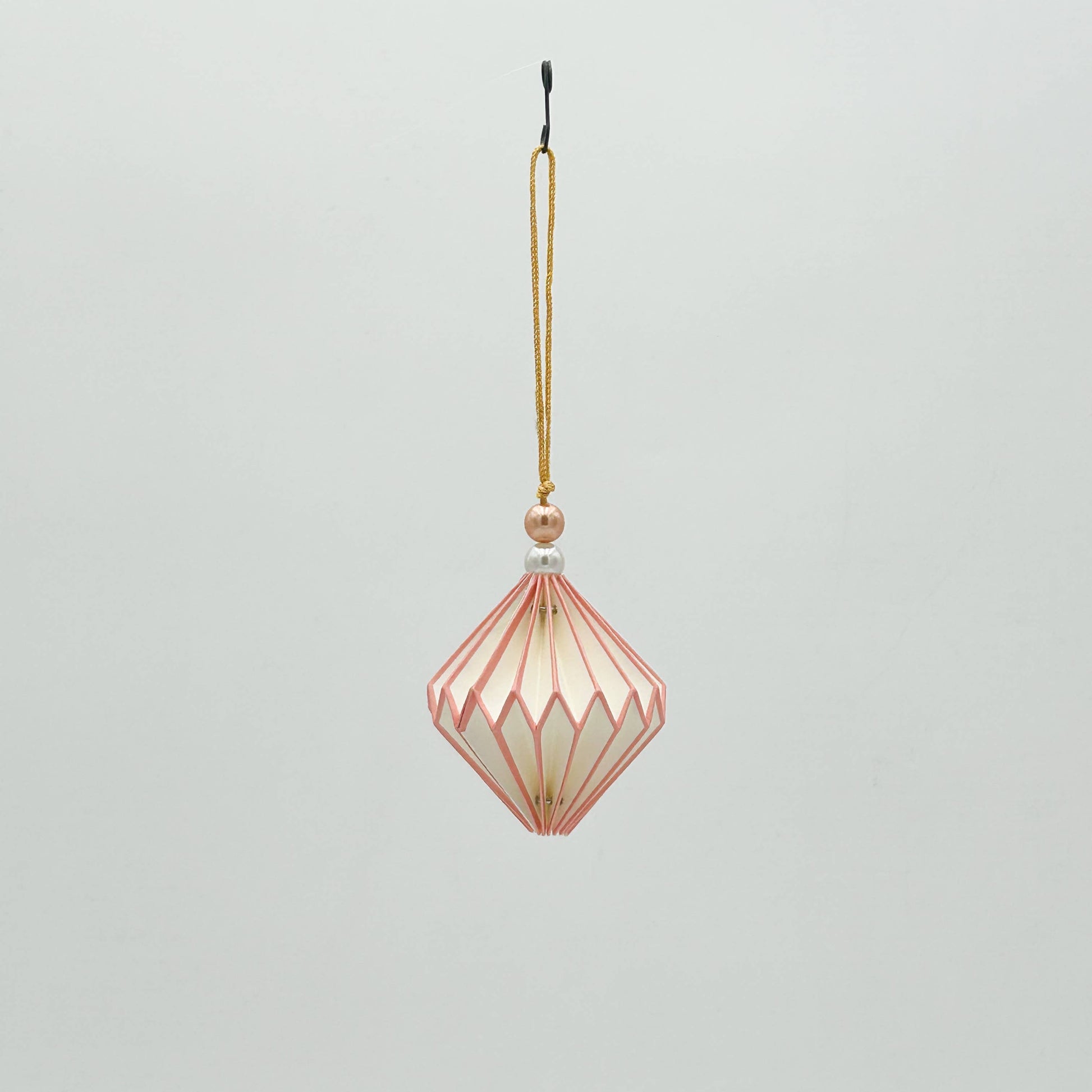 Decorative hanging ornament with geometric design on a light gray background