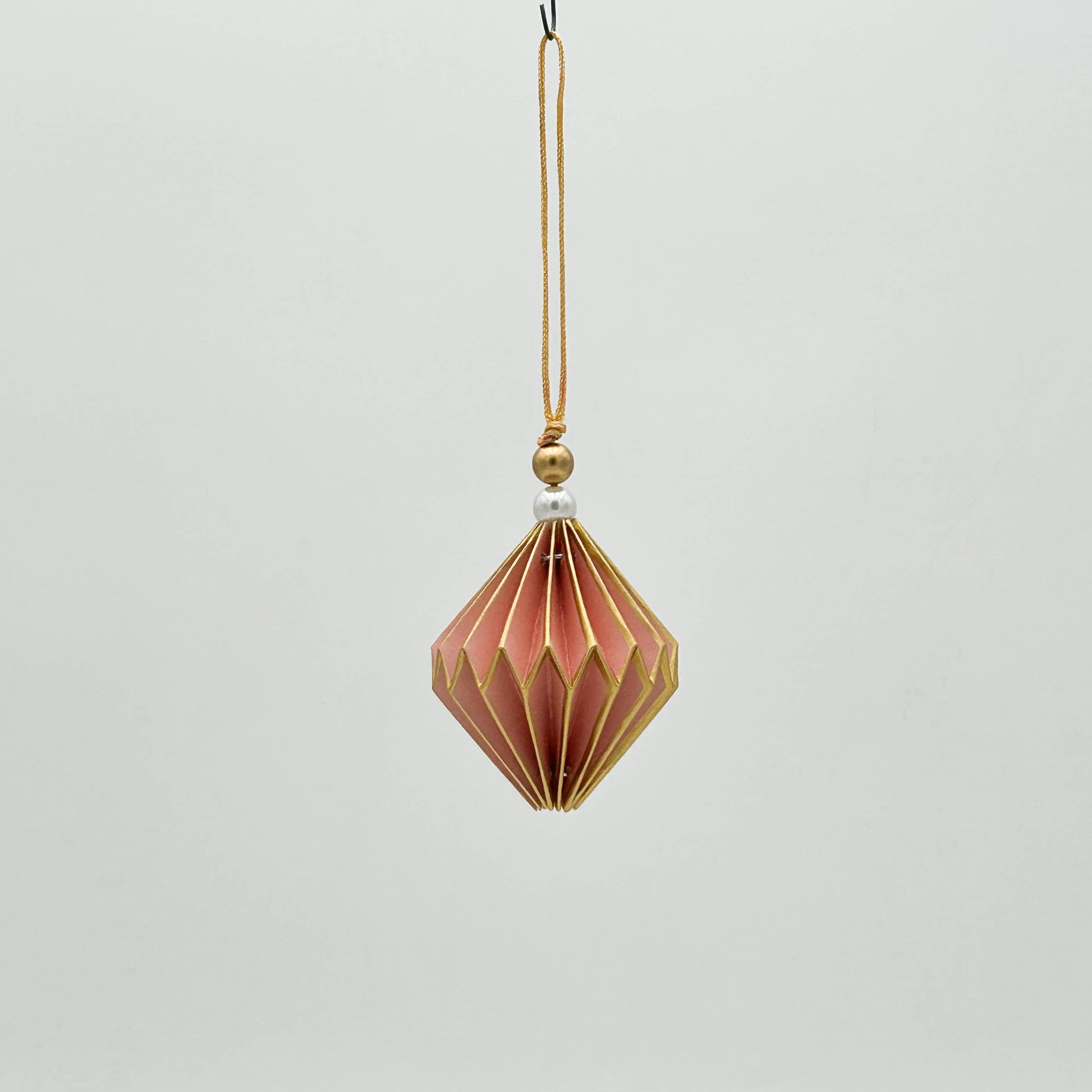 Decorative hanging ornament with geometric design on a light gray background