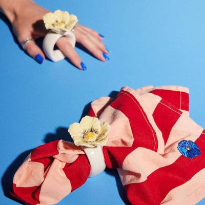 floral napkin ring made of ceramic, placed around a red and pink napkin