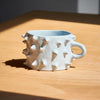 White ceramic mug with textured design on a wooden surface
