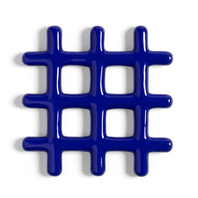a grid shaped trivet made of stoneware with a shiny royal blue glaze on a white background