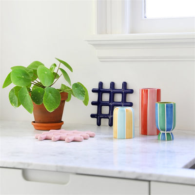 trivets with vases and a plant adorn a kitchen marble countertop